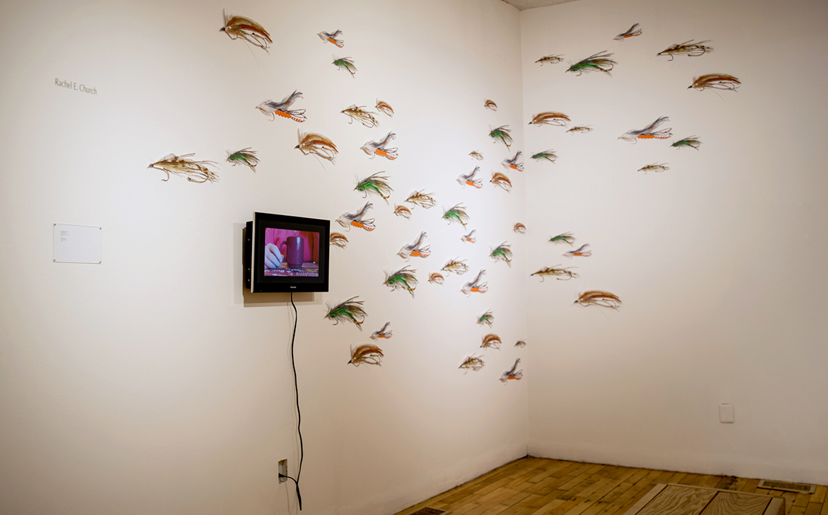 installation with wall mounted tv monitor and 55 17" long digital illustrations of fishing lures, cut out and mounted on the wall