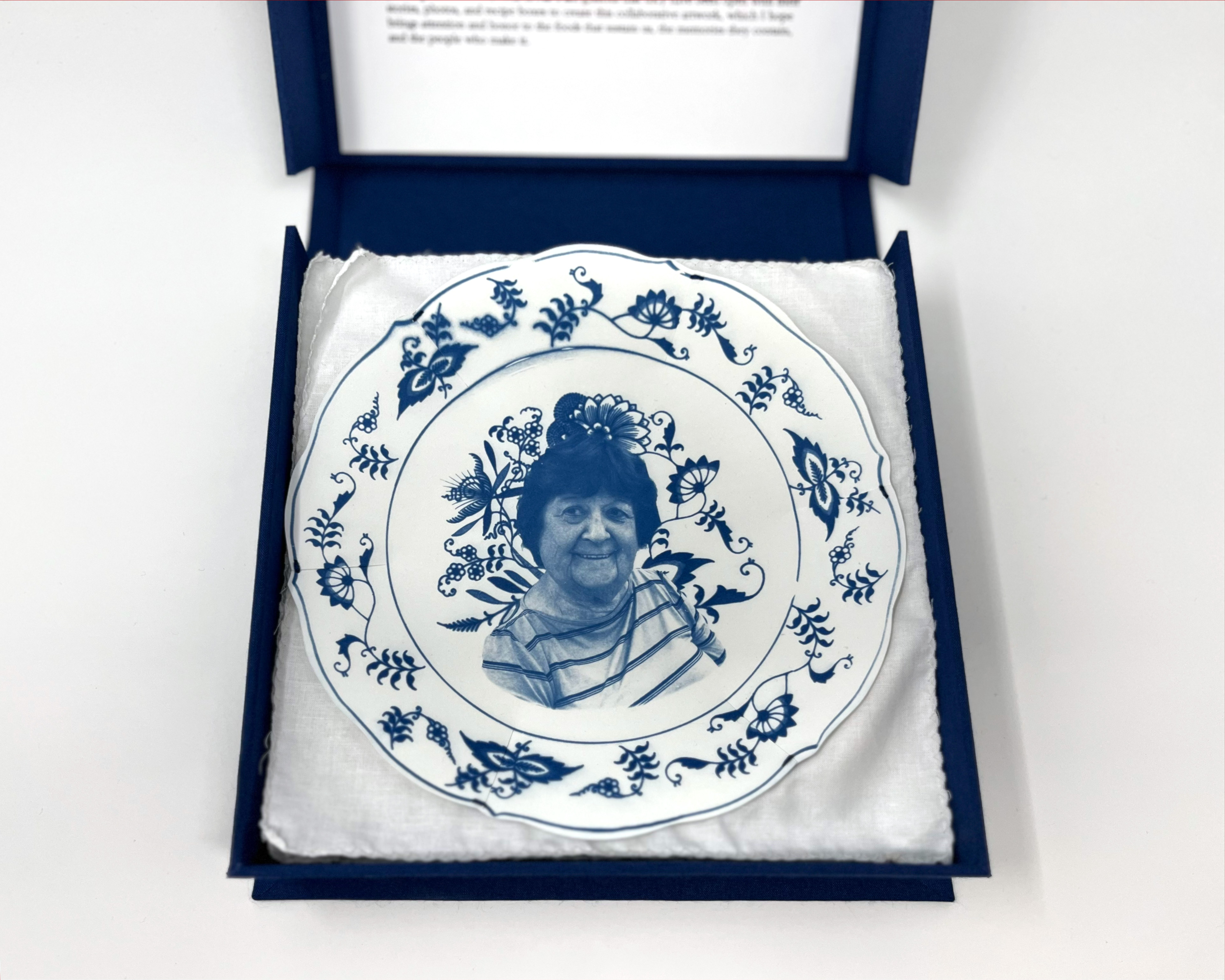 box open to show first plate: cyanotype printed plate in a blue and white china patter with a portrait of Barbara in the center