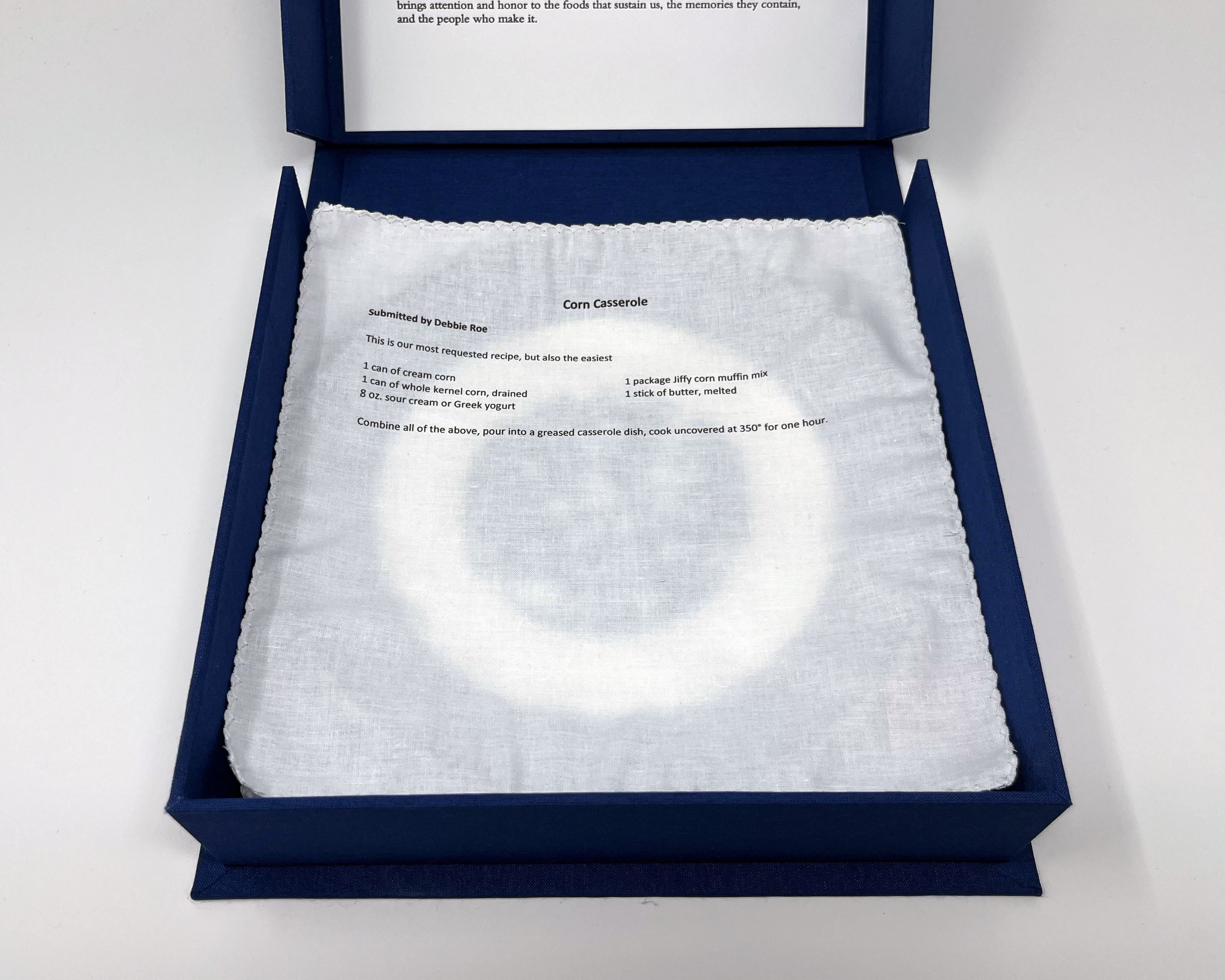 box open showing fabric liner underneath plate #6, printed with the recipe for corn casserole. Recipe in paragraph following.