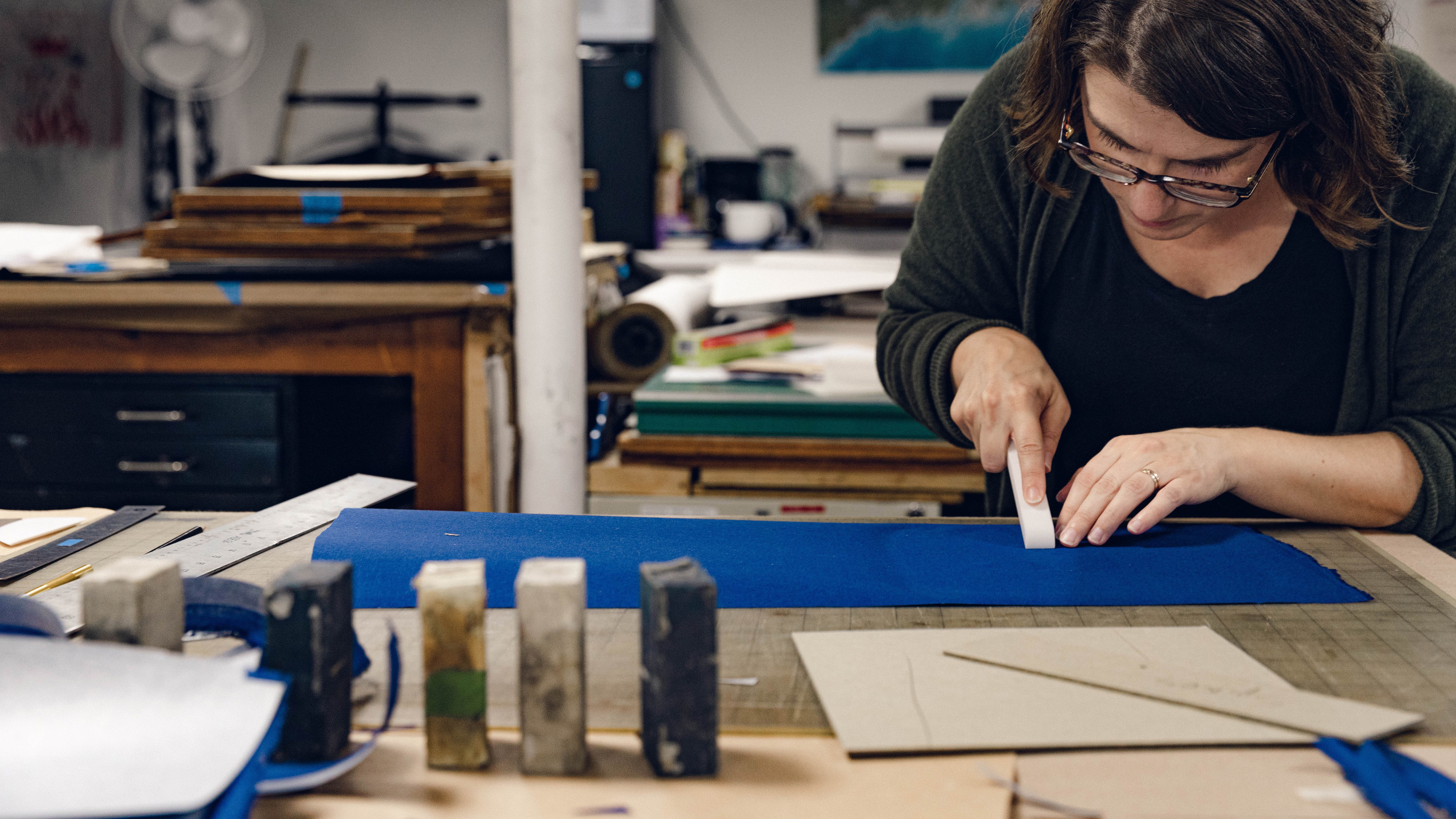 Rachel gluing up book cloth on a box cover in Maine Media's book art studio.